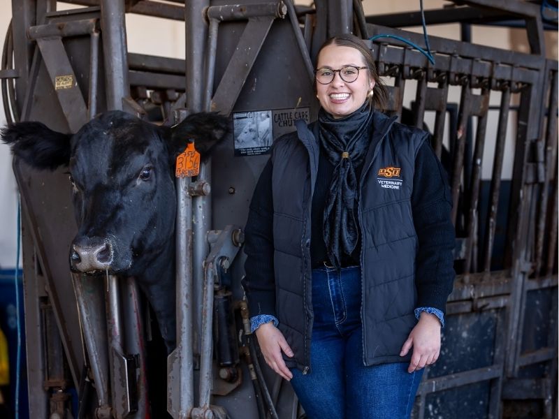 mandy lawson poses by cow in chute