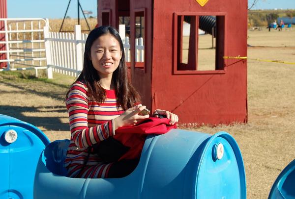 girl in striped dress rides in little train