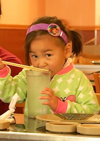 little girl in dora the explorer headband eats ice with chopsticks