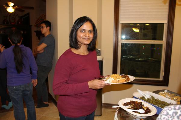 Roshini with a plate of food in a red sweater